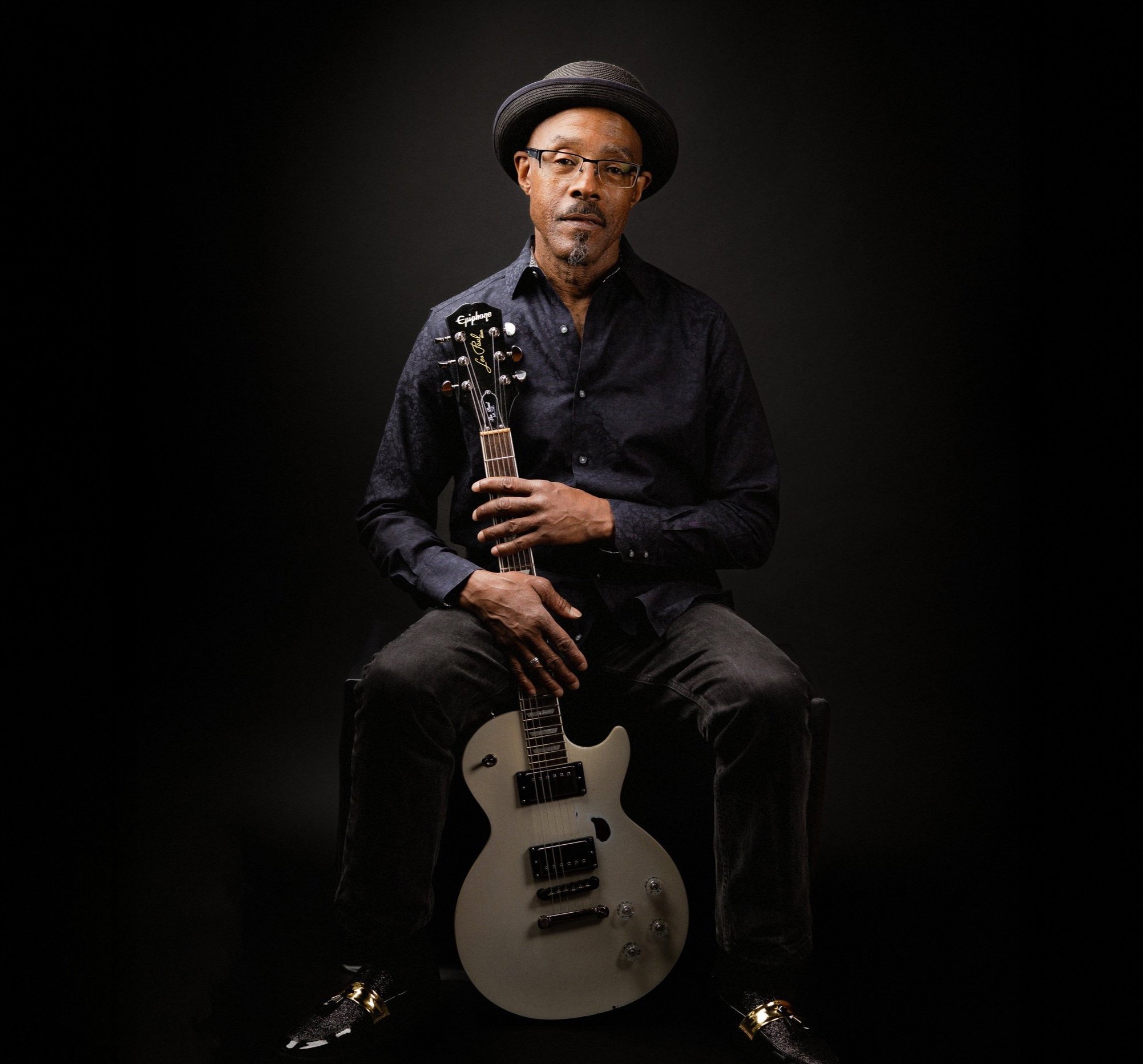 Man holding an electric guitar against a black background