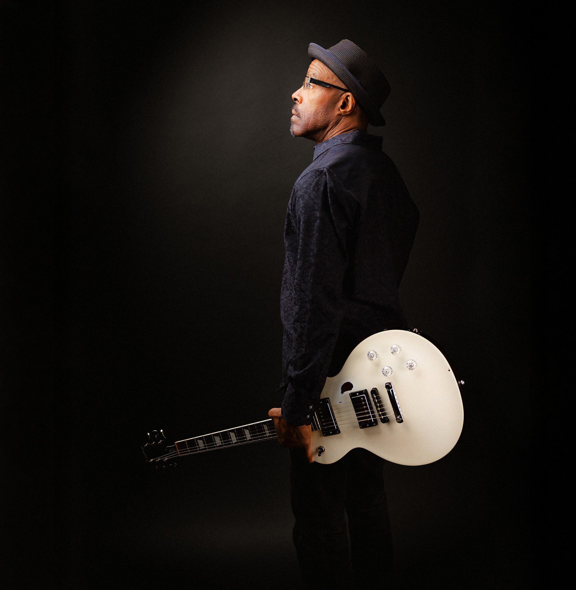 Man holding a white electric guitar in profile
