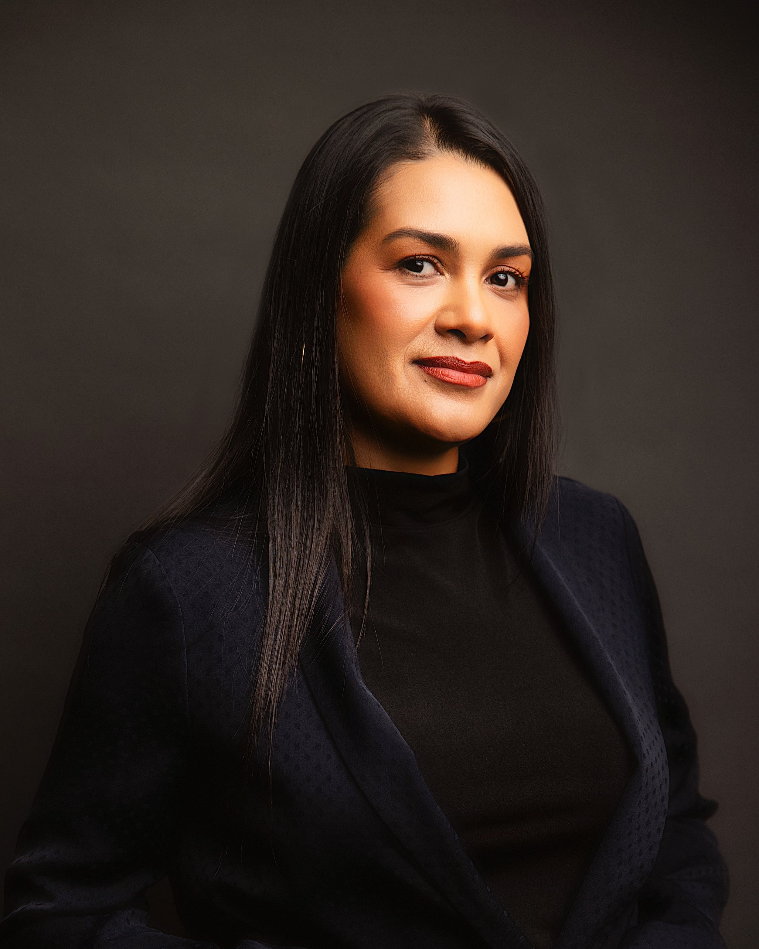 Woman with long dark hair in a dark blazer