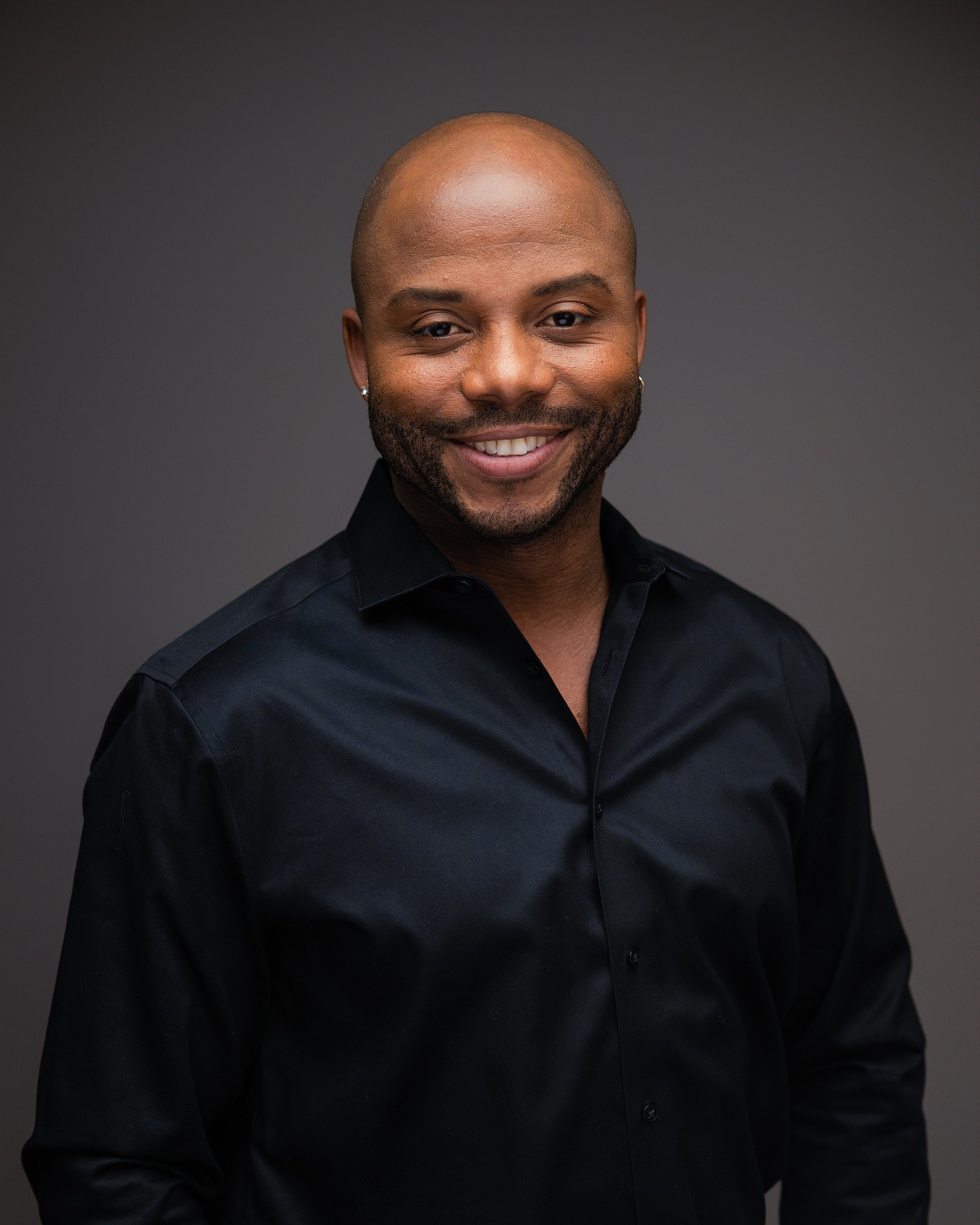 Smiling Black man with a shaved head and trimmed beard