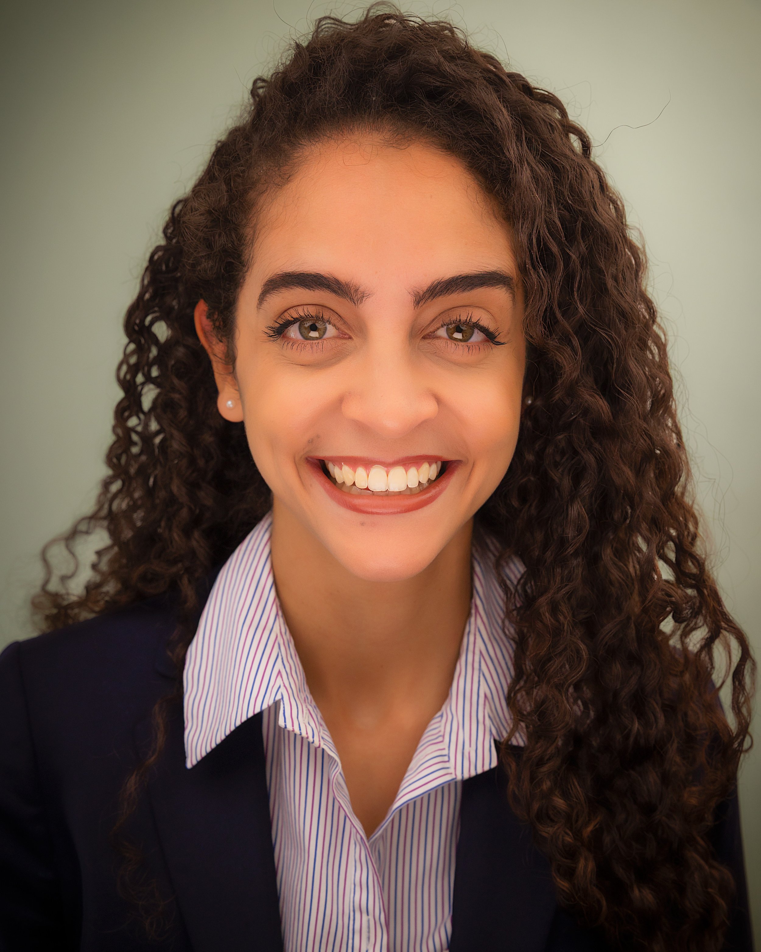 Smiling woman with curly brown hair in a navy blazer