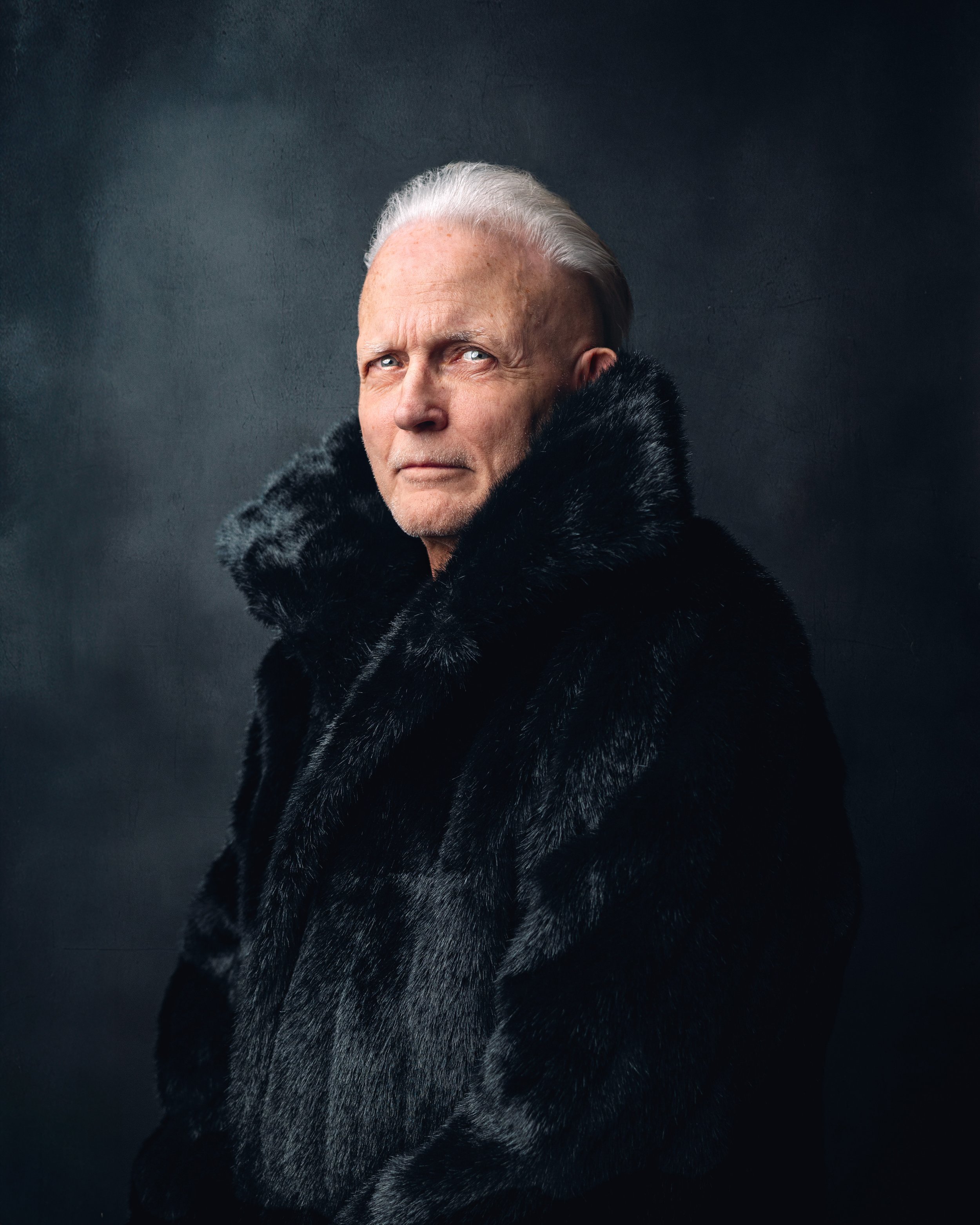 Man with silver hair in a luxurious black fur coat