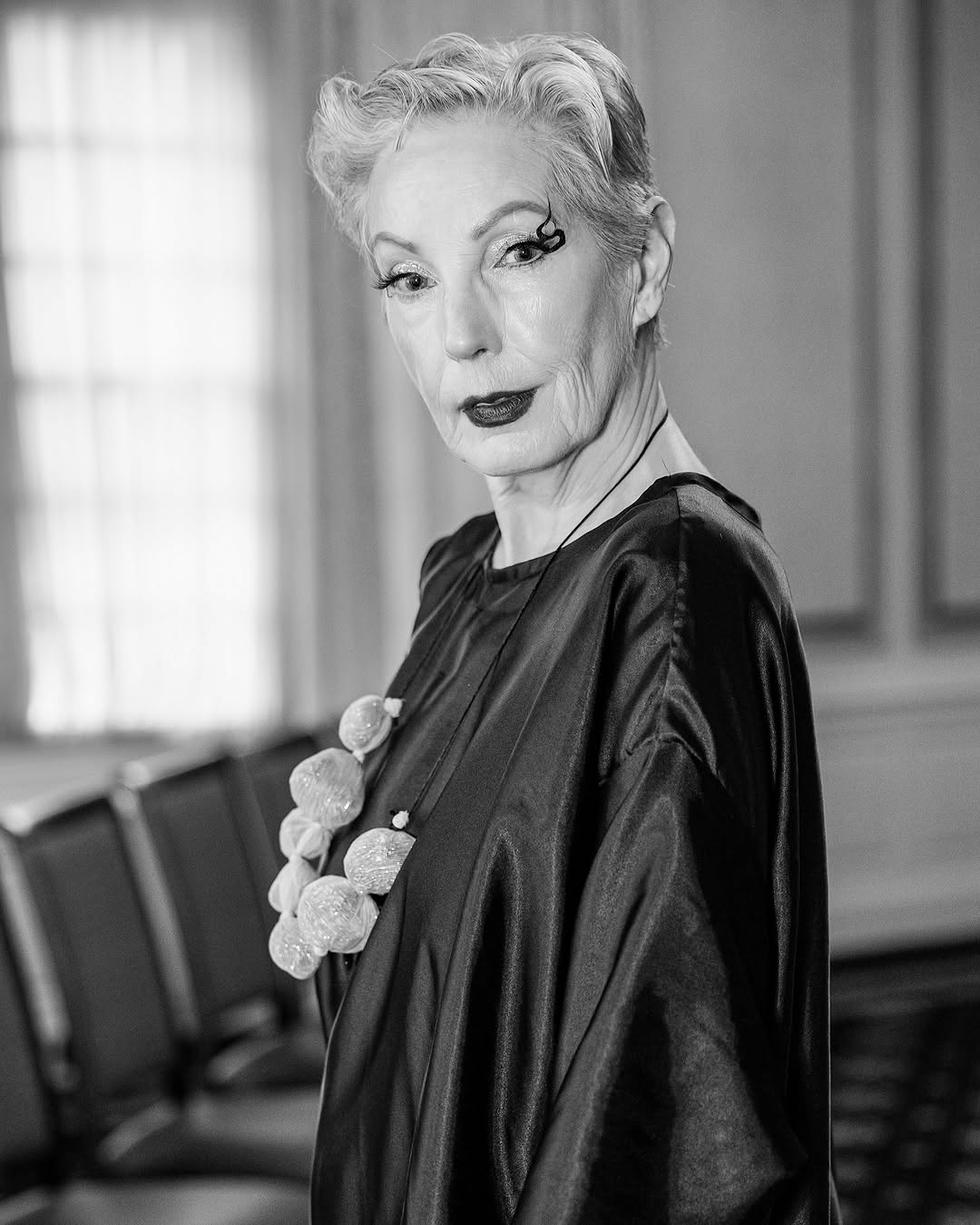 Silver-haired woman in a dramatic black-and-white fashion portrait