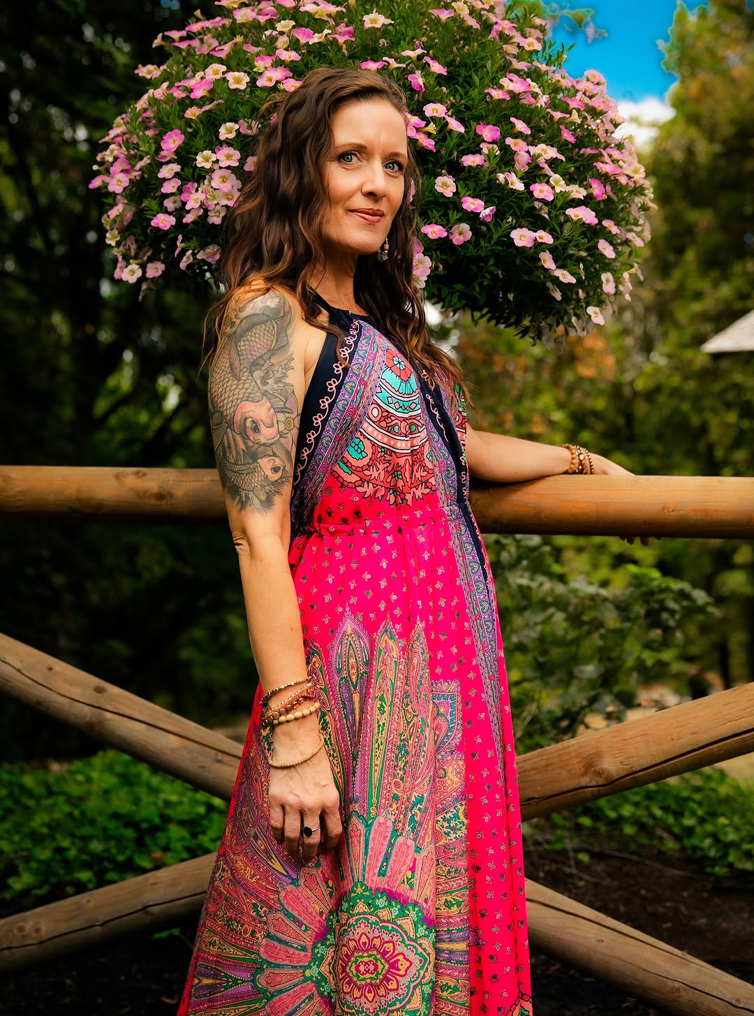Woman in a colorful patterned dress beside a wooden garden fence