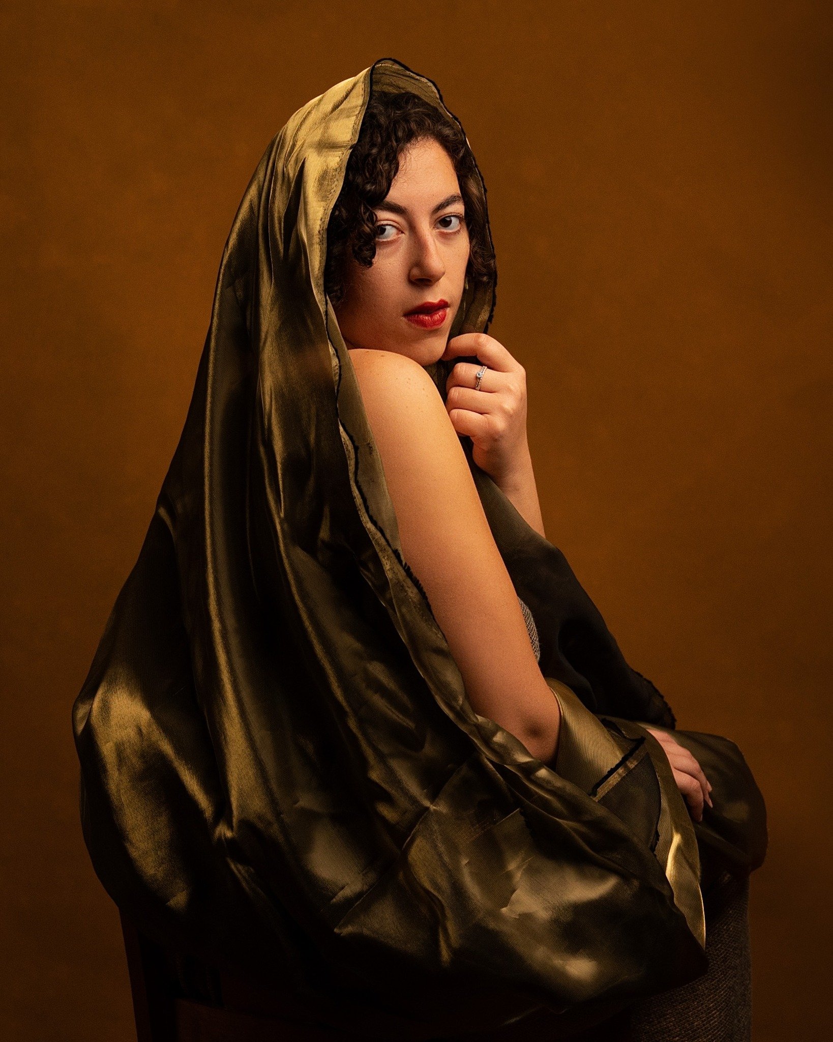 Woman in a shiny black and gold hooded garment