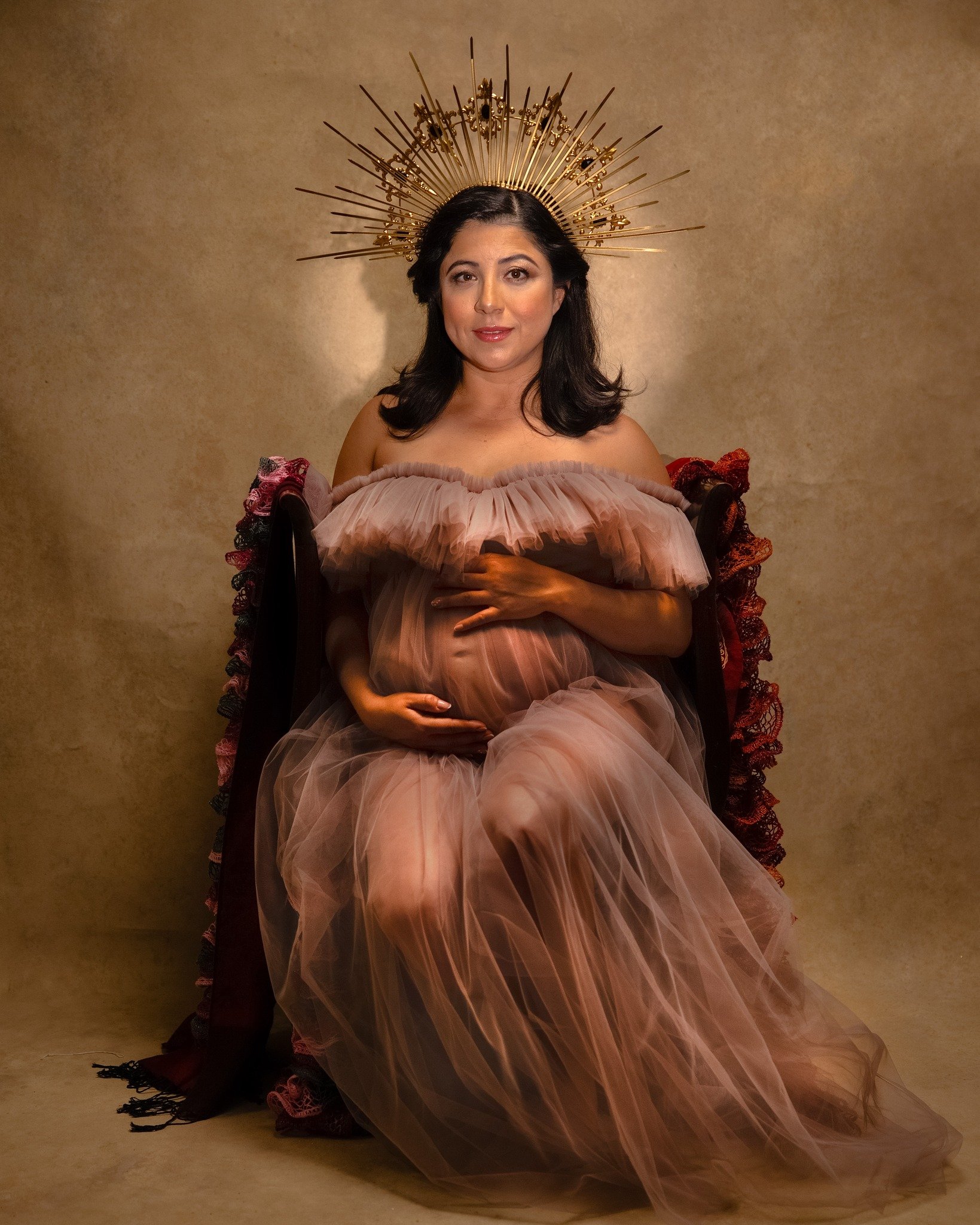 Pregnant woman in a flowing pink tulle gown with a golden headpiece